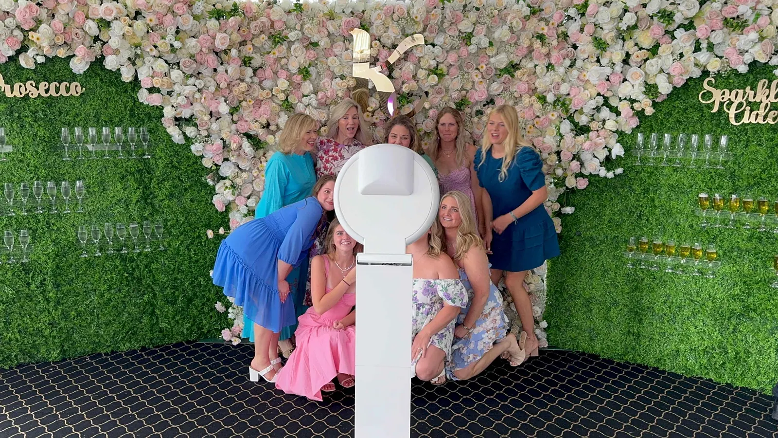 Champagne wall with flower backdrop and filled glasses at a New York event