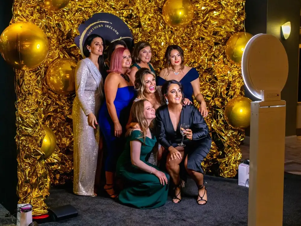 Guests posing for the studio booth in front of a gold sequin wall at a New York gala