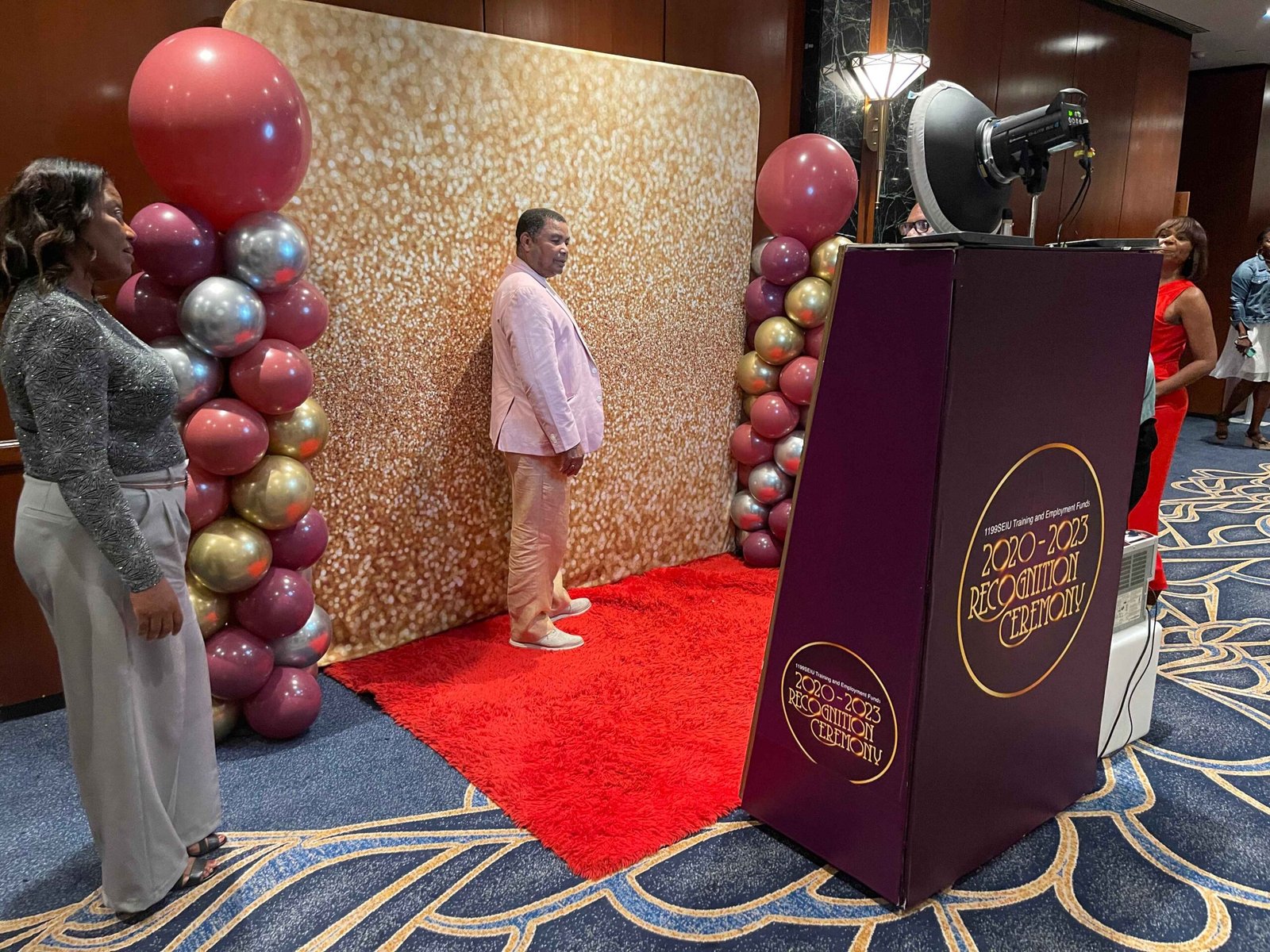 Branded booth with gold sequin backdrop and balloon styling at a gala