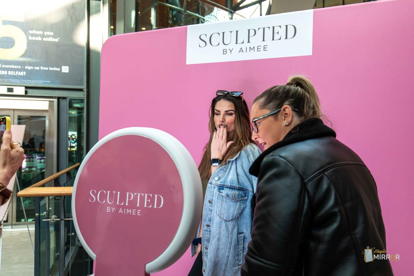 Guests posing at the Sculpted by Aimee branded photo booth wall