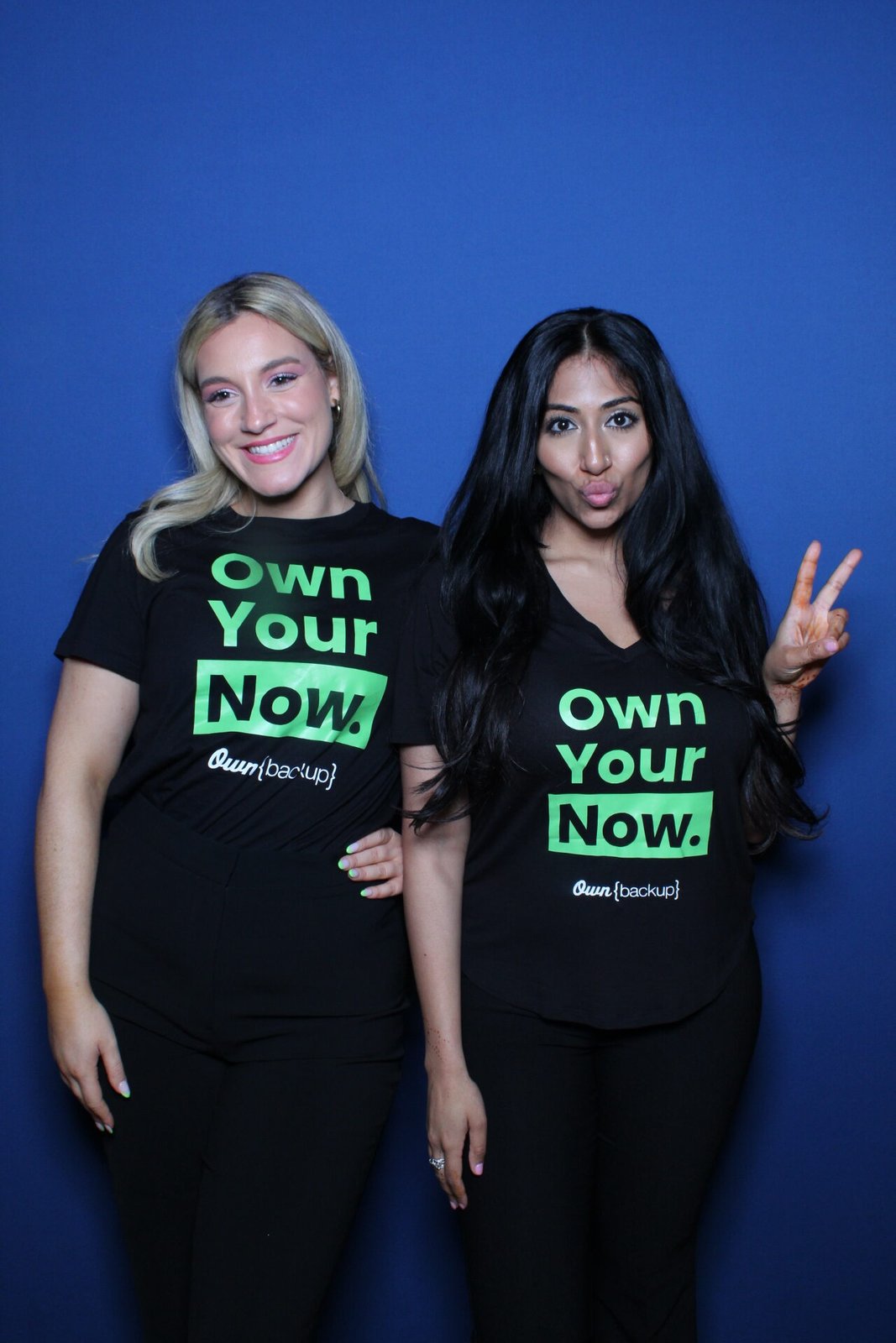 Guests in branded shirts posing at a conference photo booth
