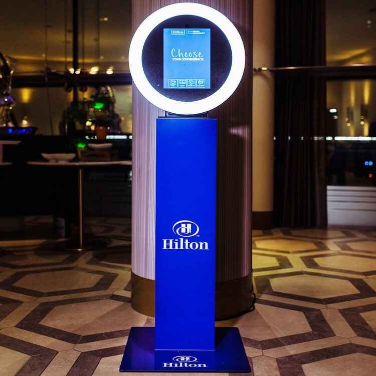 Hilton-branded ring light photo booth in a hotel lounge