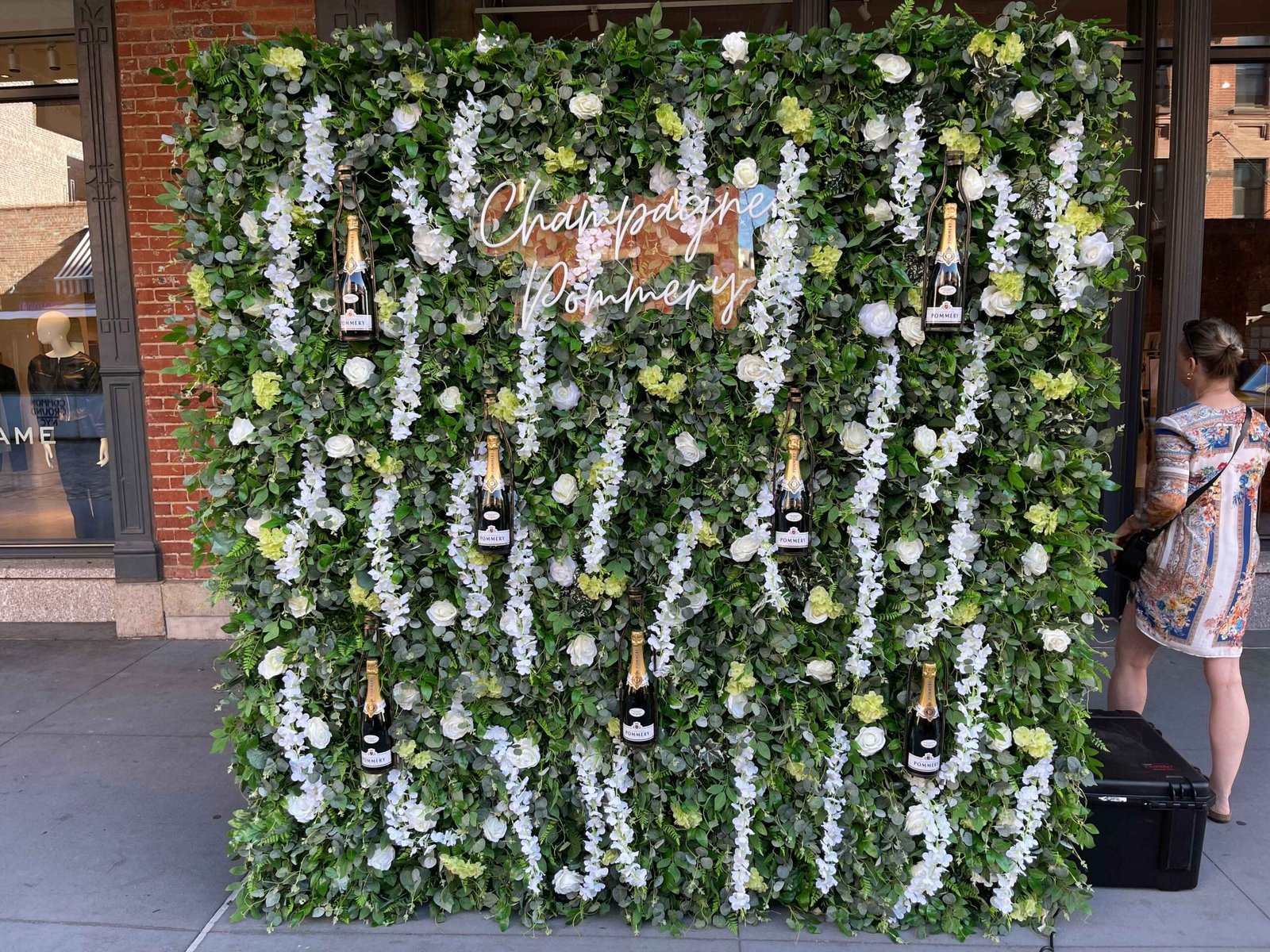 Champagne wall with custom signage and greenery backdrop