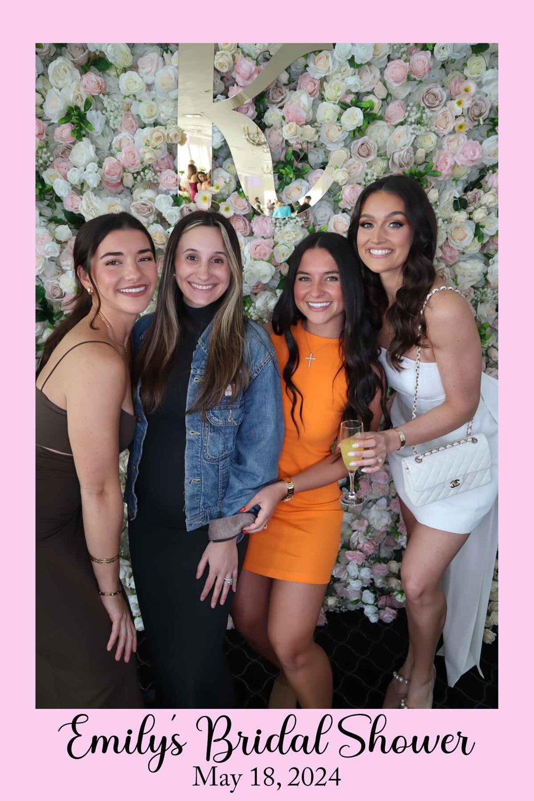 Friends celebrating in front of the flower wall at a champagne event