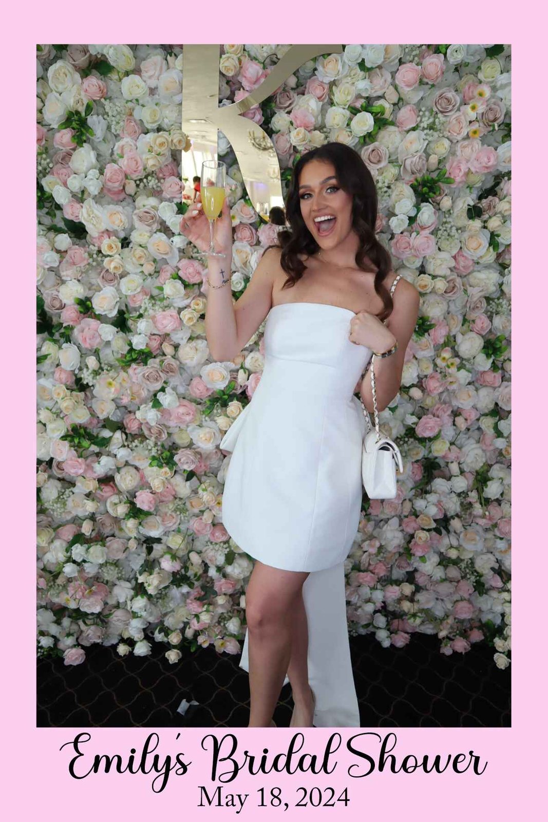 Guest posing at the flower wall with a glass of champagne