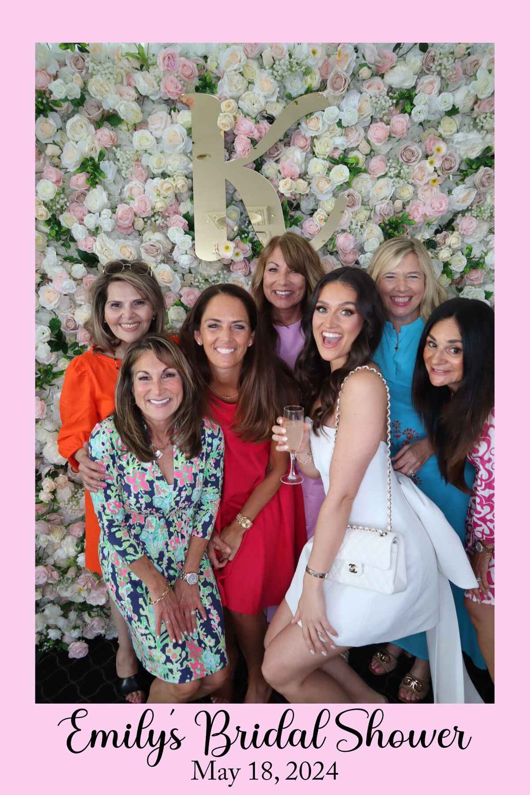 Group celebrating at the flower wall with champagne