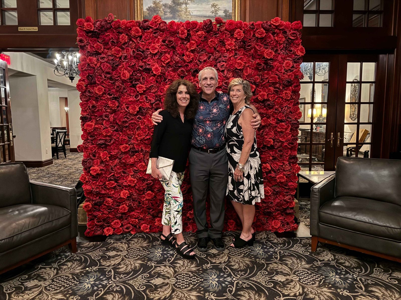 Guests posing at a red flower wall in a hotel venue