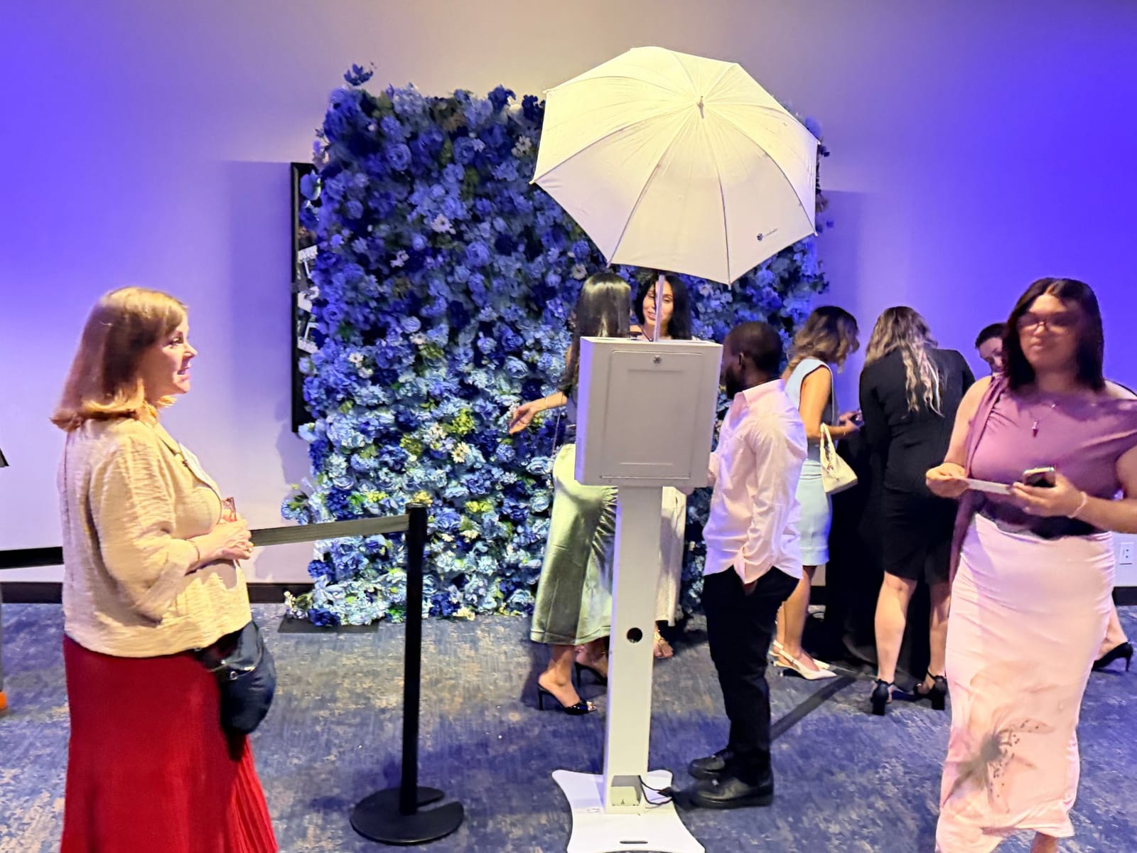 Guests taking photos at the blue flower wall during a reception