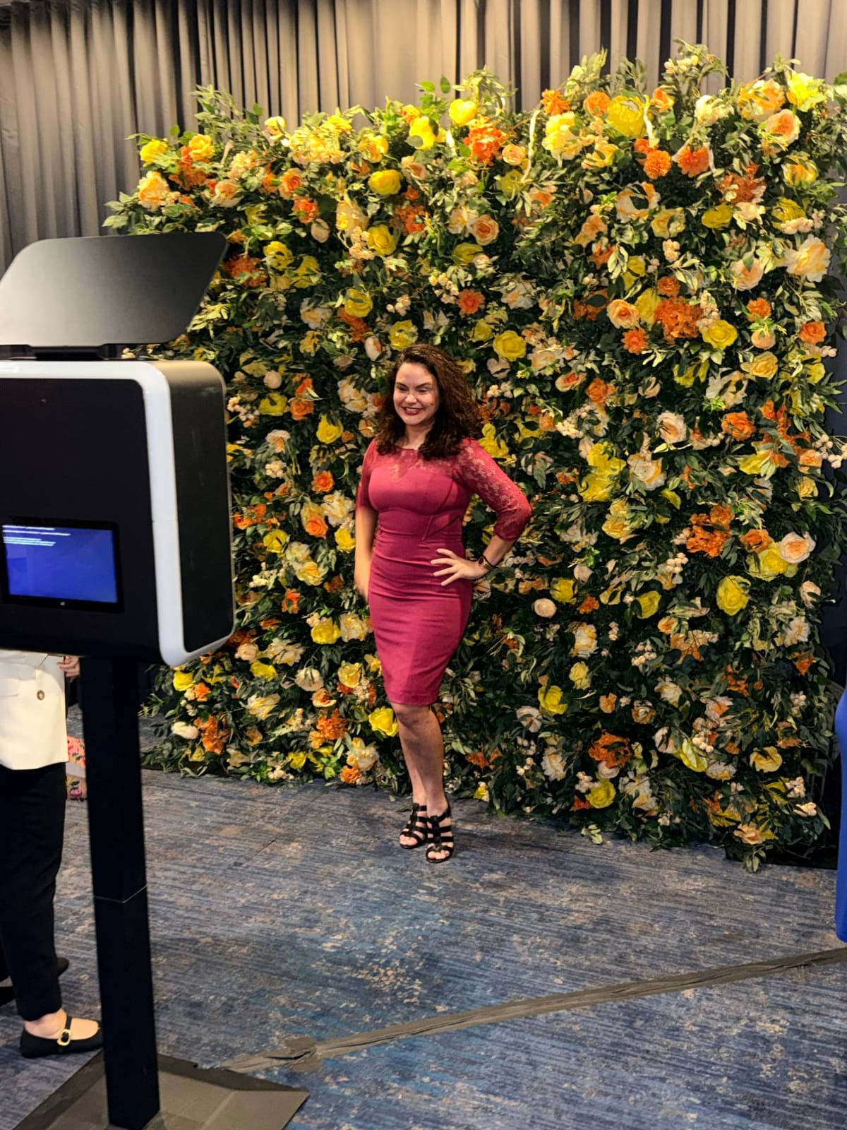 Yellow and orange flower wall with photo booth at a corporate event
