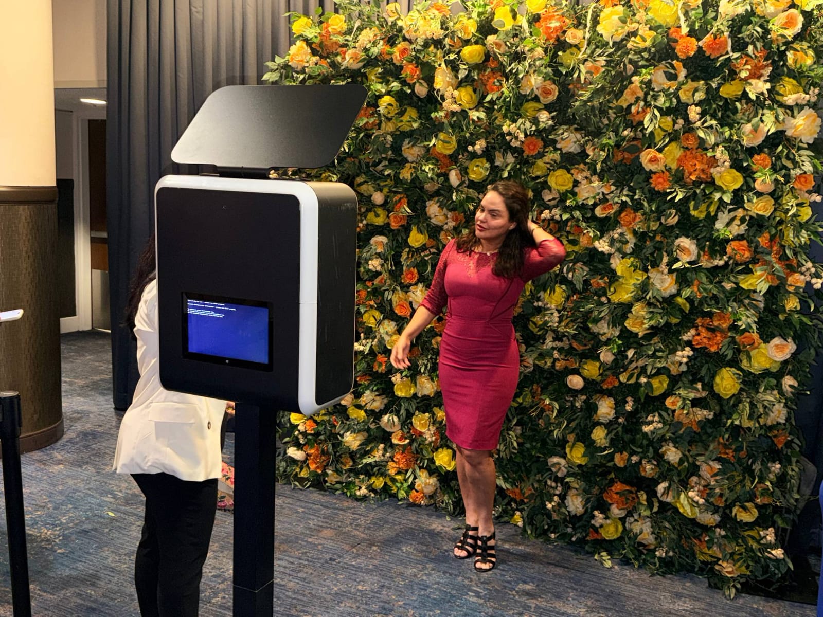 Guest posing at the yellow and orange flower wall photo booth