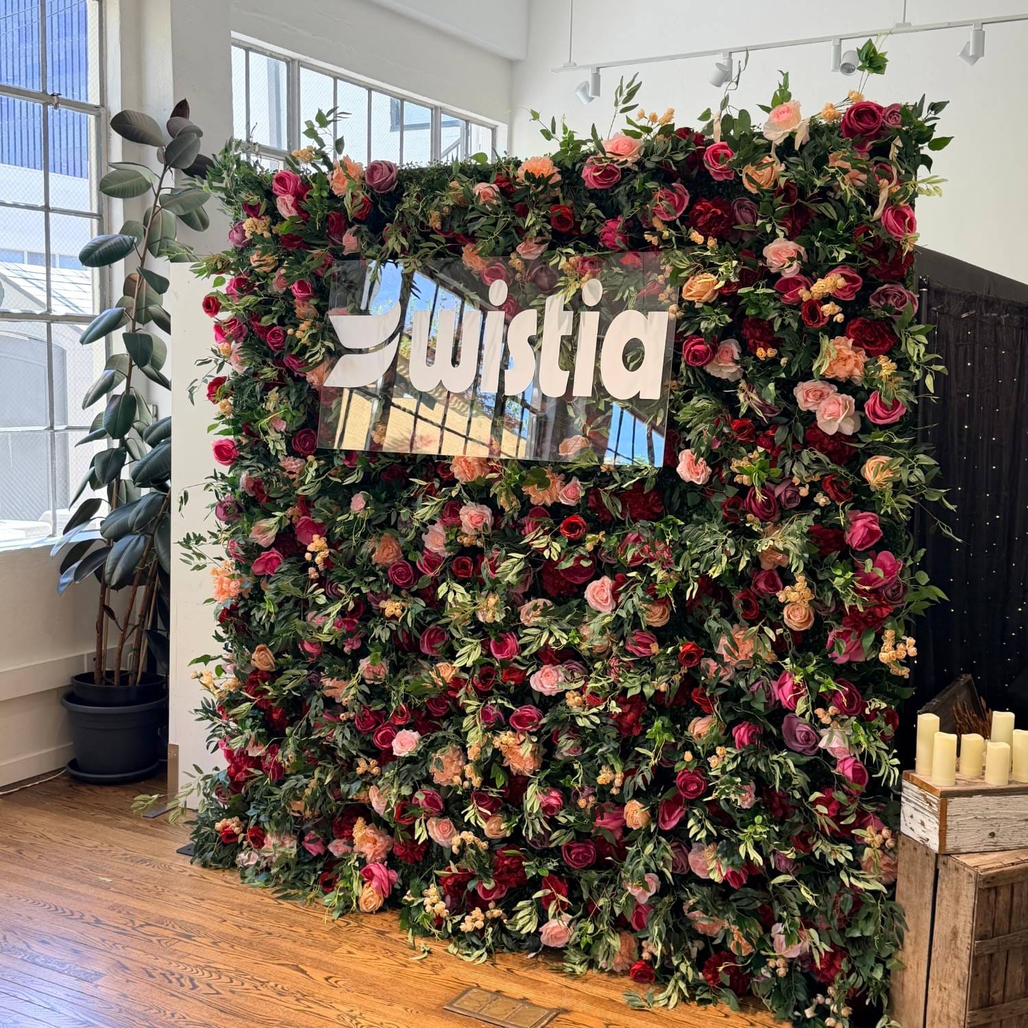 Flower wall with custom acrylic company logo at a brand activation