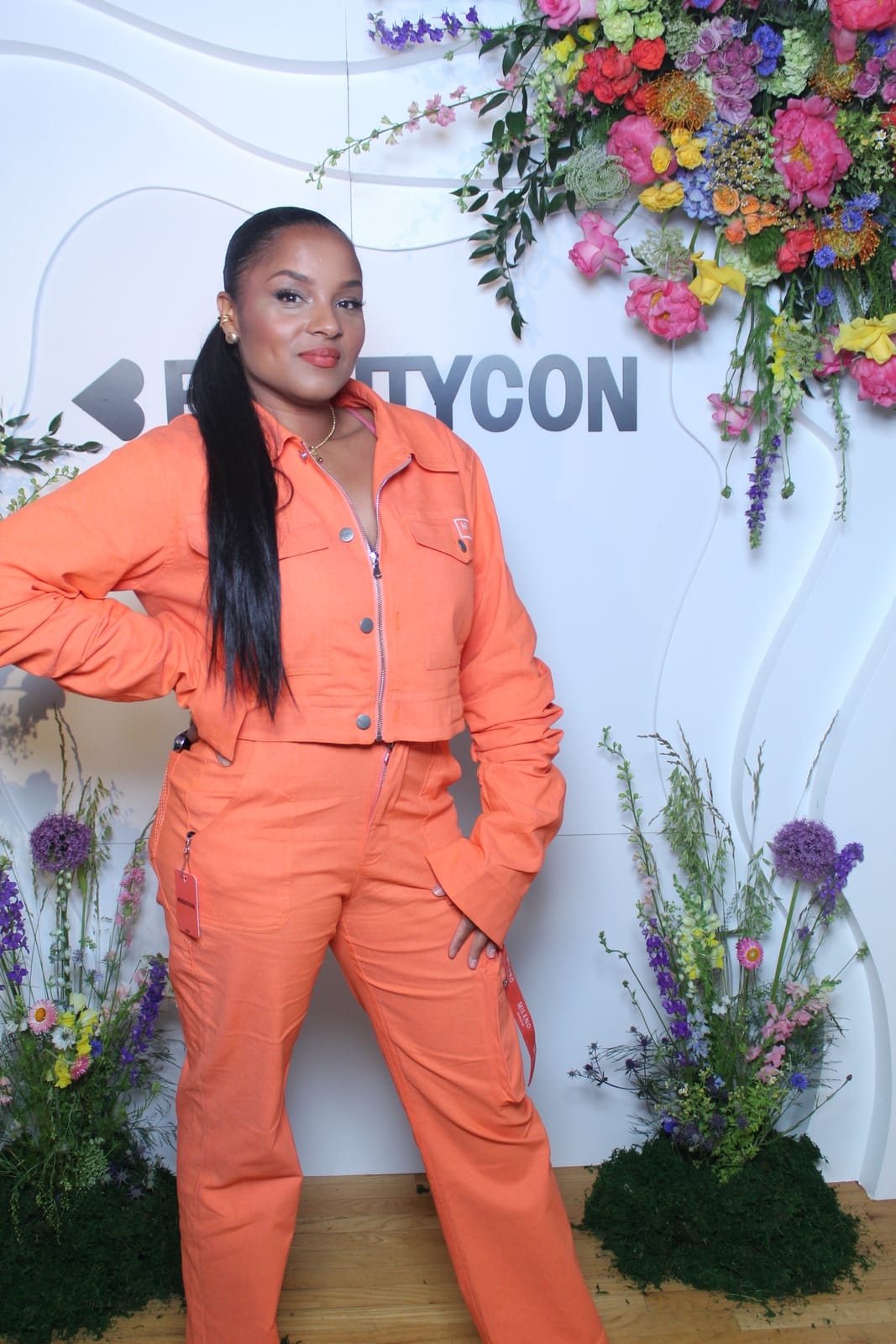 Guest in an orange jumpsuit at the Beautycon step-and-repeat