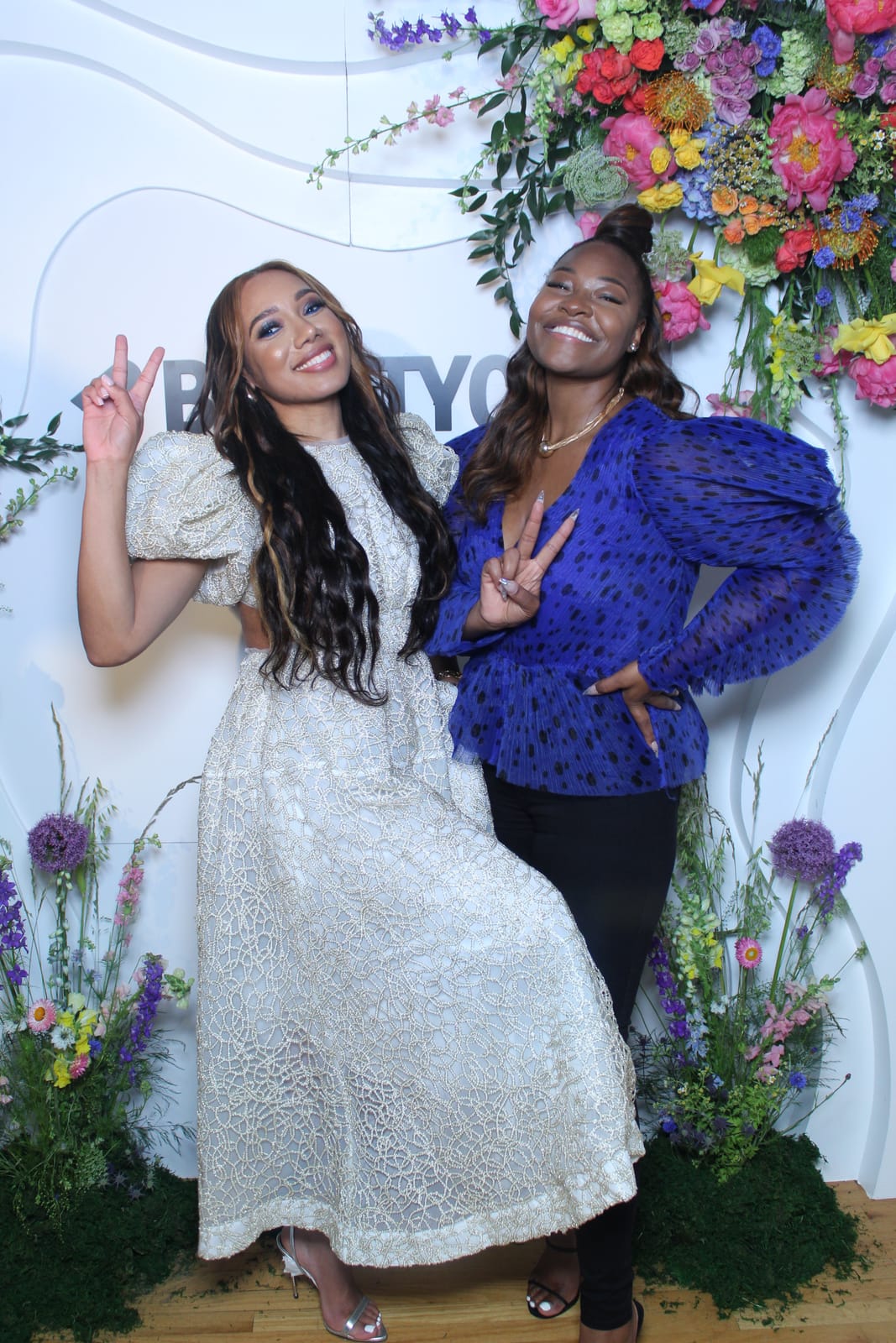 Two attendees at the Beautycon photo booth, one in a blue gown