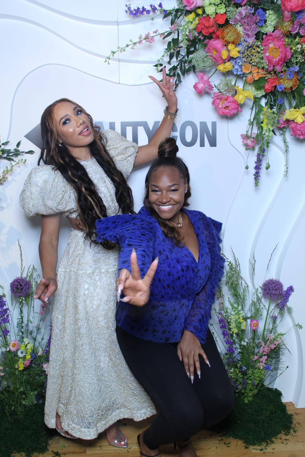 Three guests posing together at the Beautycon convention booth