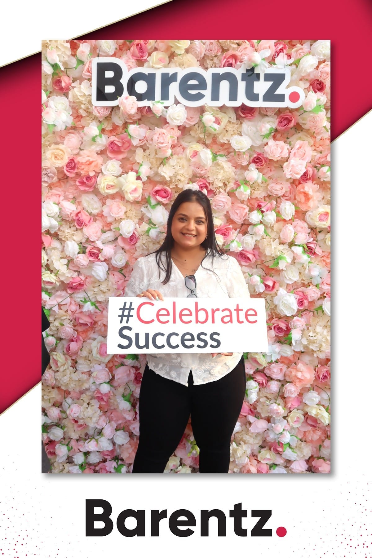 Guest holding a Celebrate Success sign at the Barentz flower wall