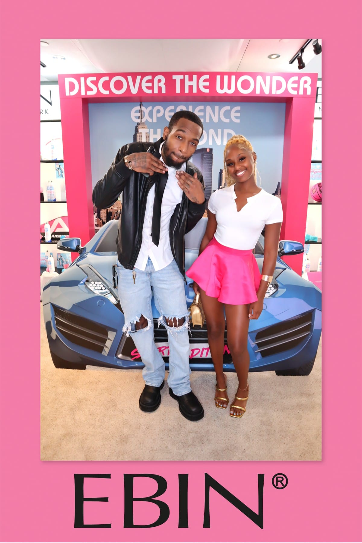 Couple posing at the EBIN New York sports-car photo prop — Discover the Wonder backdrop