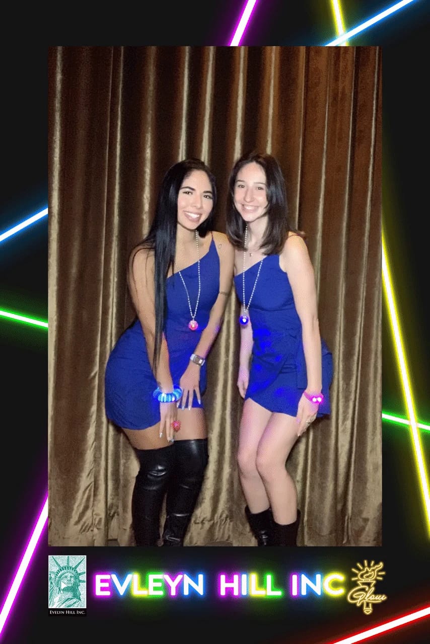 Two friends in blue dresses with glow necklaces at the Evelyn Hill Inc company dinner