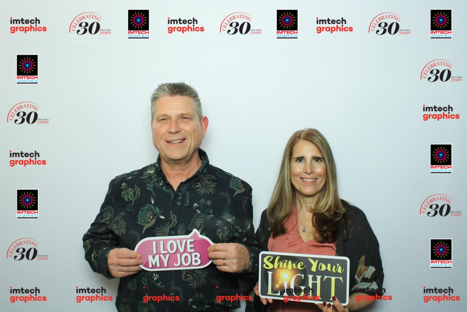 Two colleagues posing at the Imtech Graphics 30th anniversary step-and-repeat