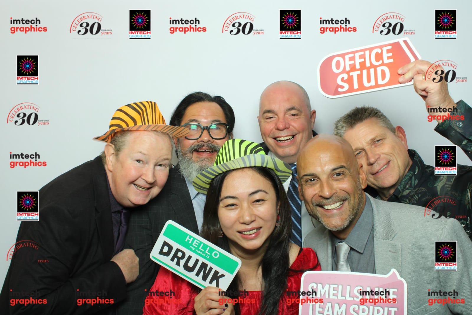 Colleagues in zebra-print hats posing with an Office Stud prop at the Imtech Graphics booth
