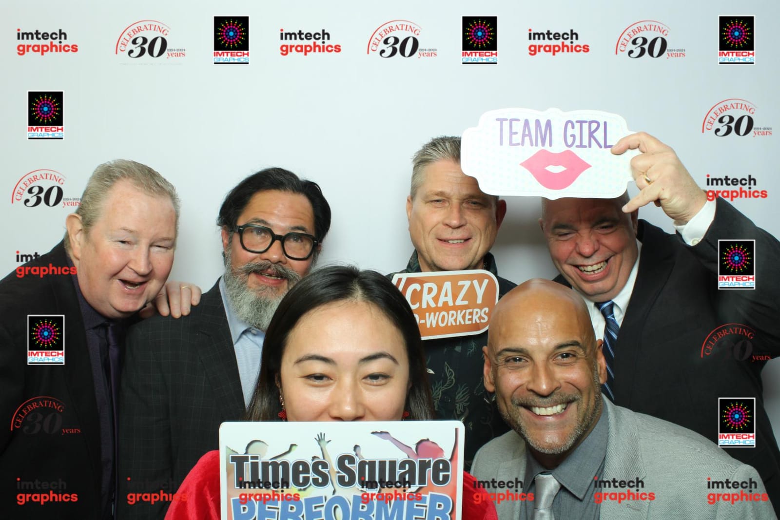Colleagues posing with a Team Girl prop at the Imtech Graphics 30th anniversary celebration