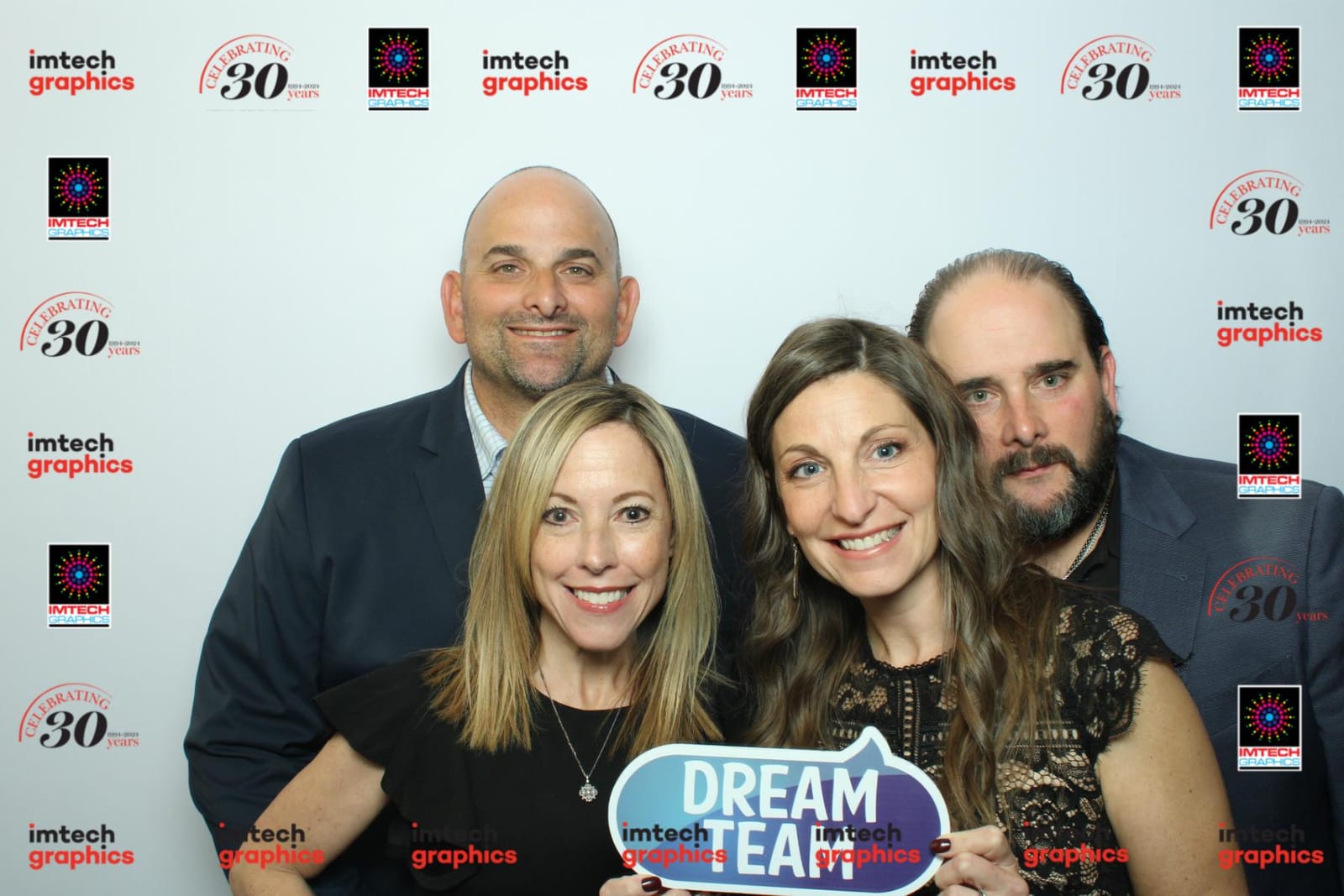 Colleagues in animal-print hats posing with a Dream Team prop at the Imtech Graphics anniversary booth