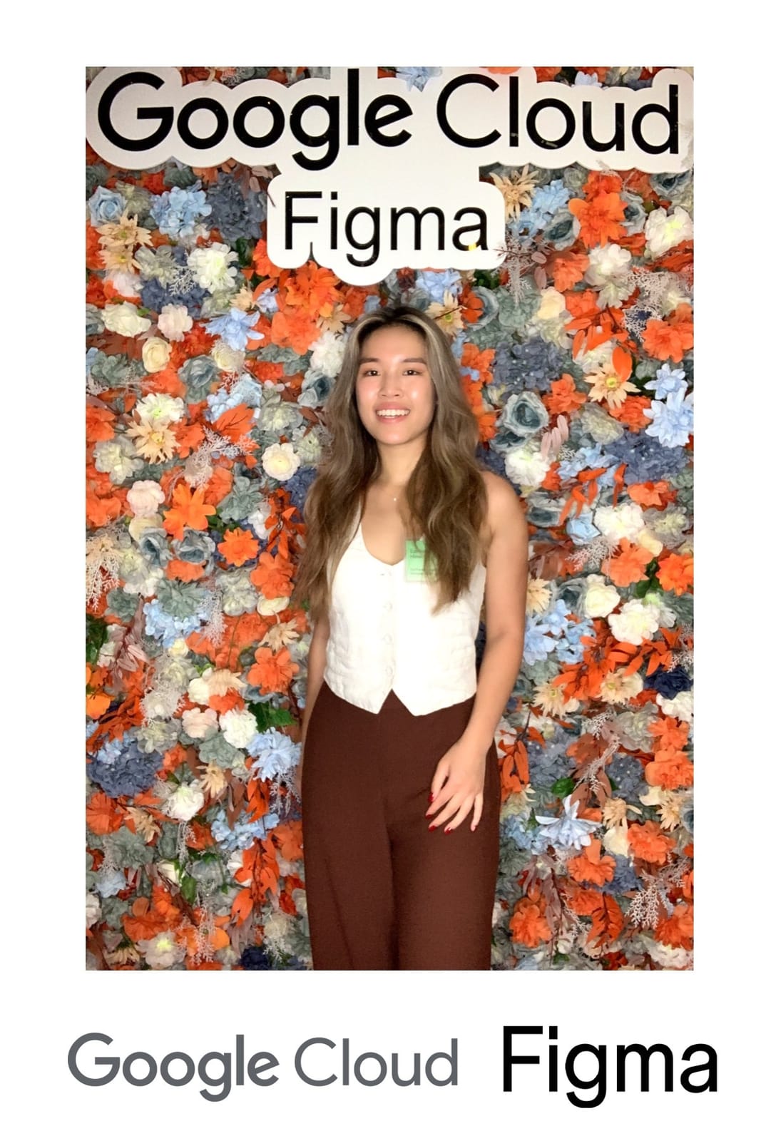Guest smiling in front of the orange and blue flower wall at the Google Cloud × Figma event