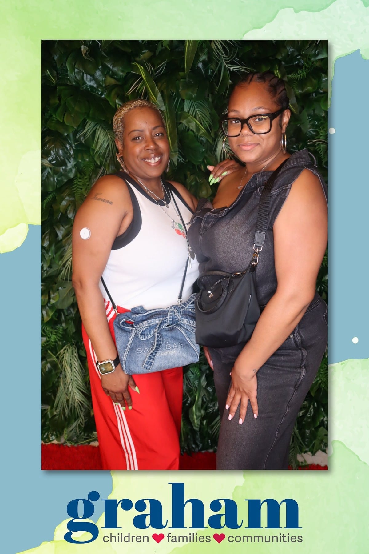 Two guests posing at the Graham celebration — greenery wall