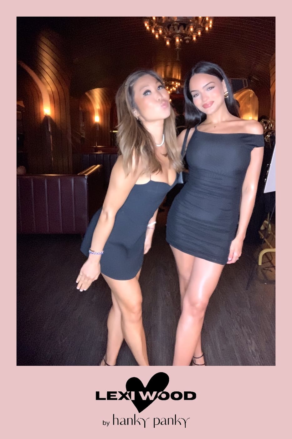 Two friends in black mini dresses posing for the booth