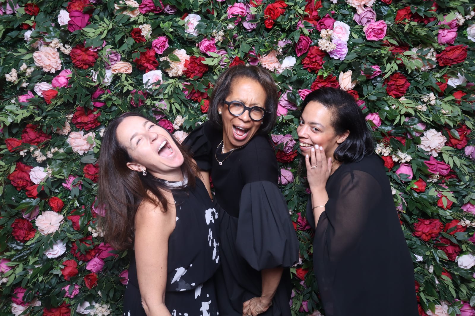 Three guests laughing together at the Love Story rose flower wall