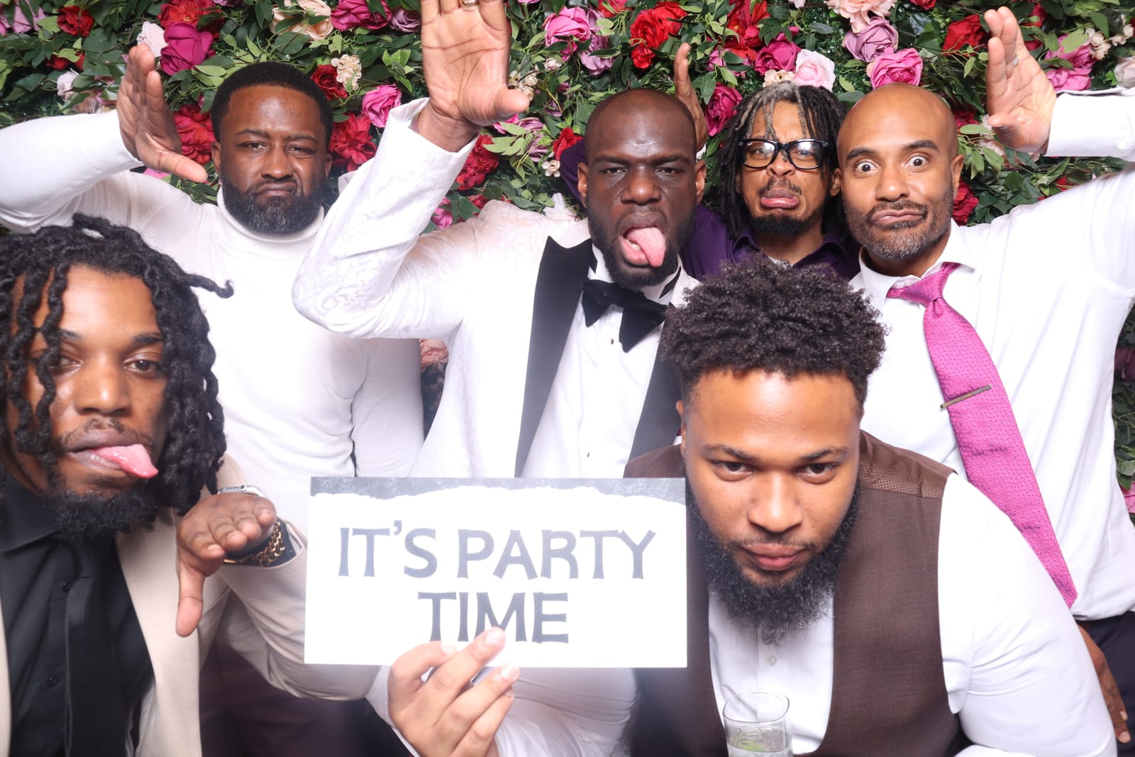 Group of guests making faces with an It's Party Time sign at the Love Story photo booth