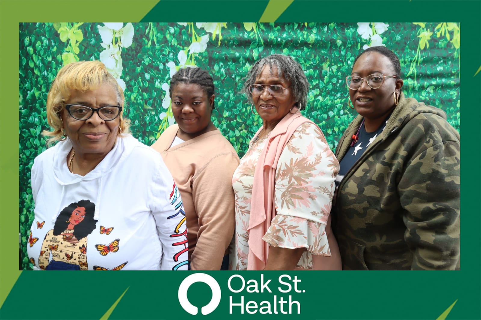 Four Oak St. Health team members posing together at the green flower wall