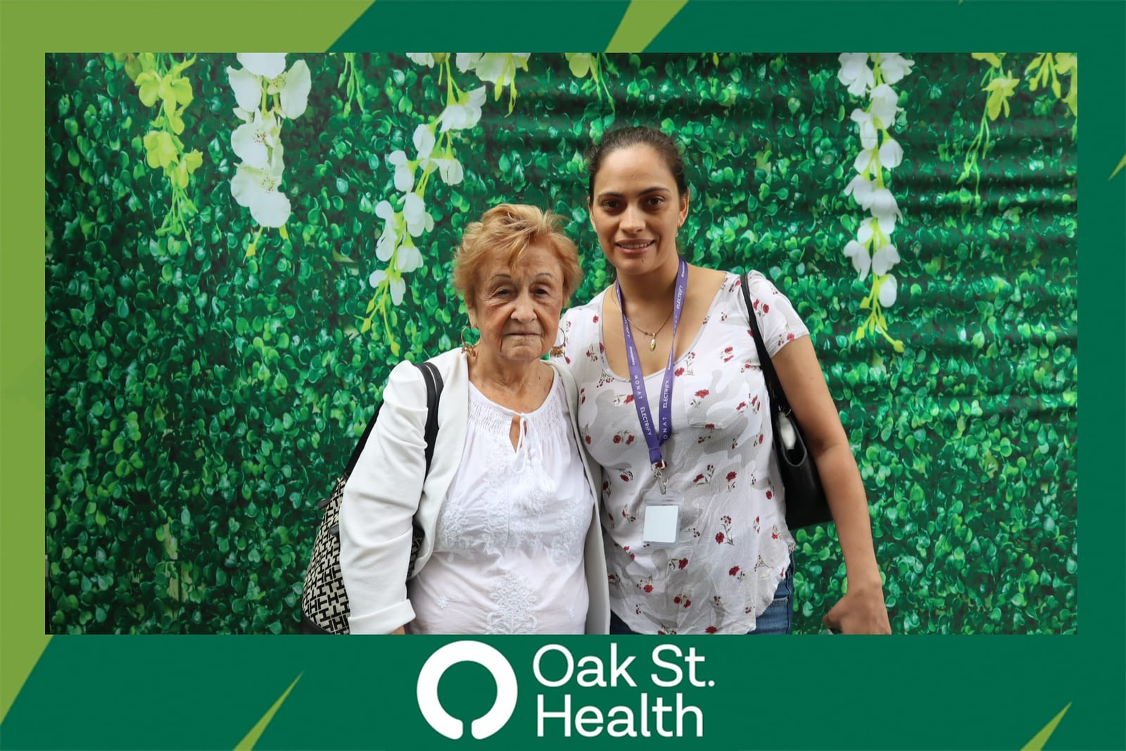 Four Oak St. Health team members posing together at the flower wall booth