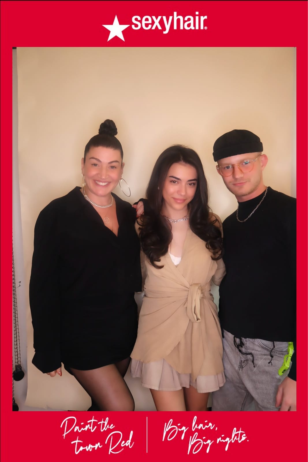 Three SexyHair team members posing together, one in a beige wrap dress