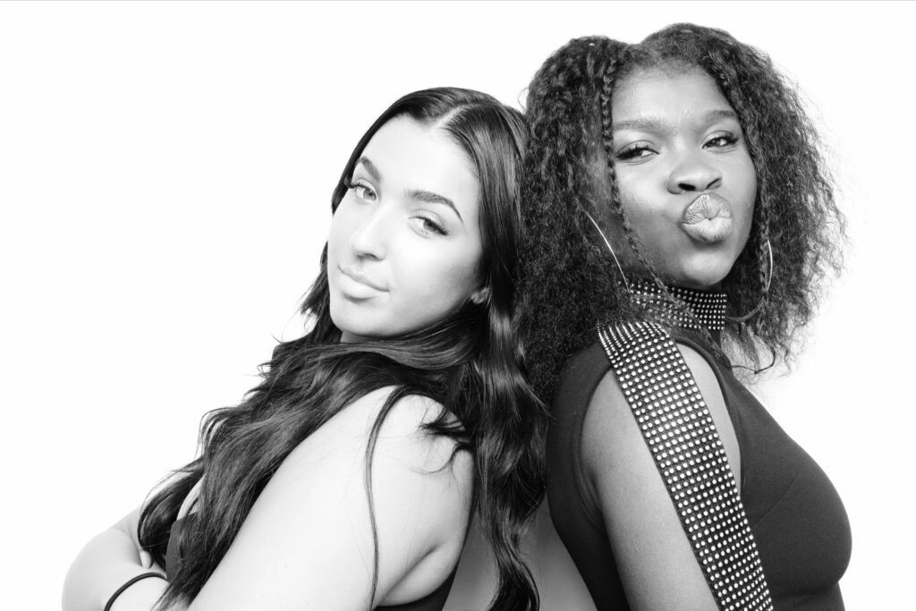 Two friends back to back in a high-key black-and-white glam booth portrait