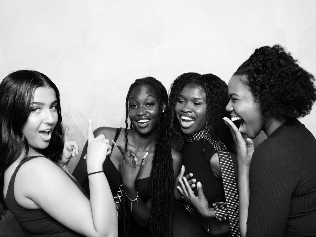 Group of friends laughing during a glam booth session at an NYC event