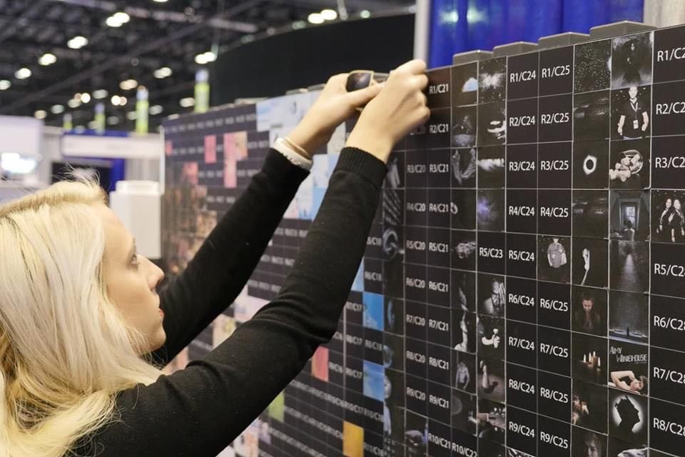 Guest placing a photo sticker on the mosaic wall at a trade show