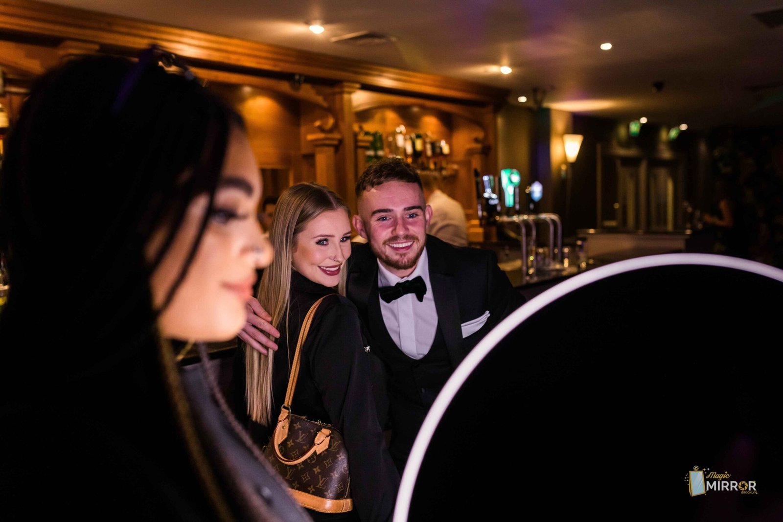 Friends posing with the roaming booth at an evening event