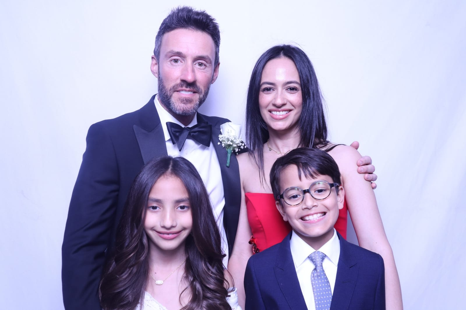 Family of four dressed up in the wedding photo booth against a white backdrop